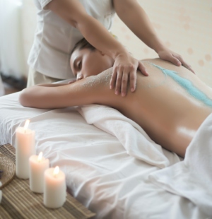 Beautiful woman getting a salt scrub beauty treatment in the health spa.