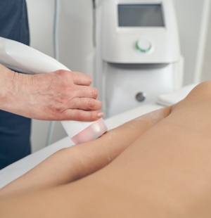 Beauty treatment of young woman in modern clinic with hand probe